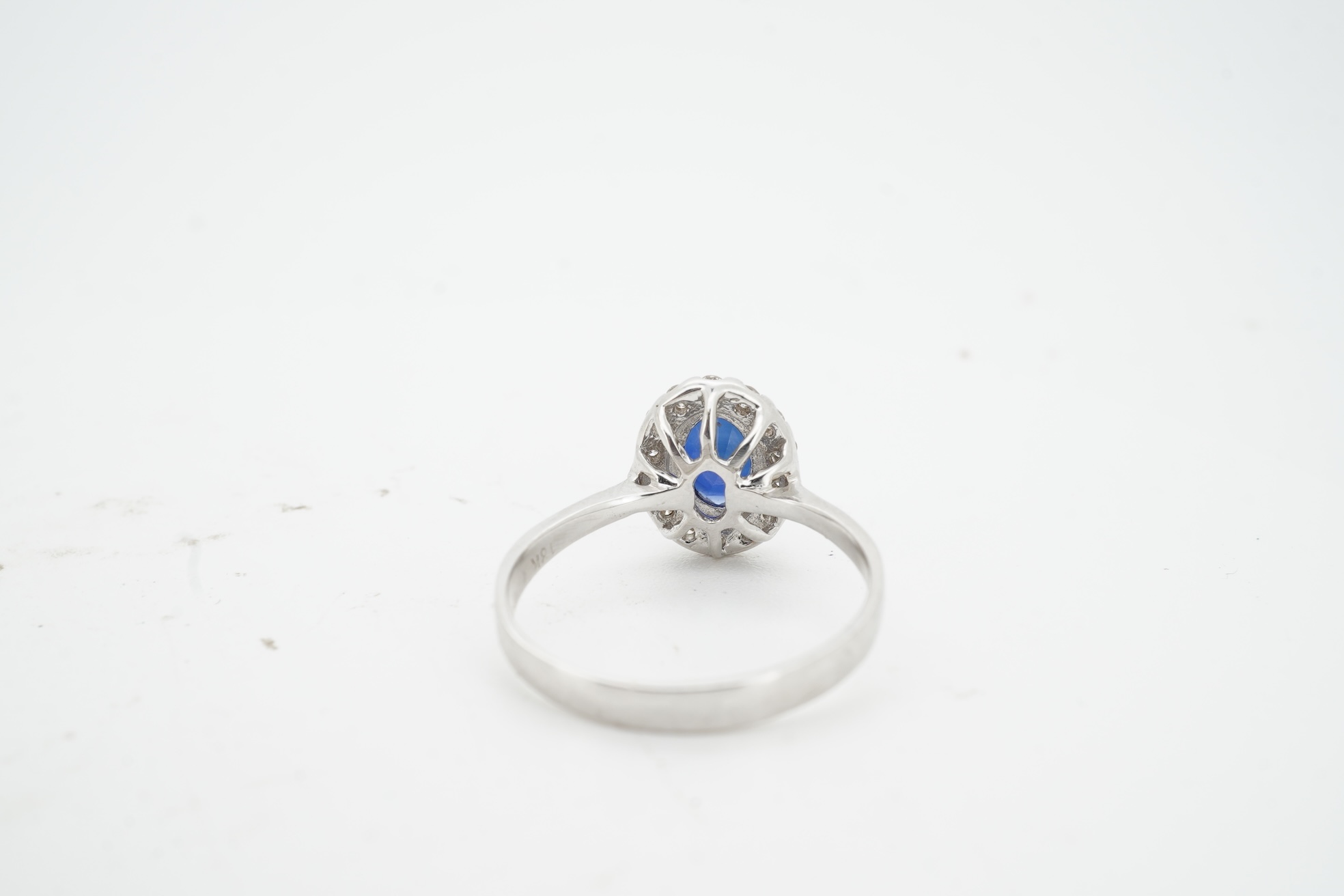 A synthetic sapphire and diamond cluster ring, mounted in white gold, size L1/2, stamped 18K, gross weight approximately 1.5 grams
